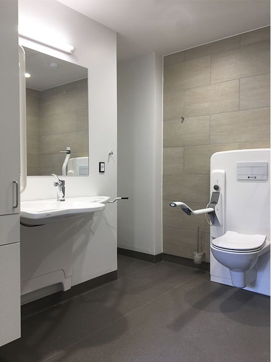 Dementia-friendly bathroom at Stenslundcentret with ROPOX SupportLine washbasin and toilet lifter