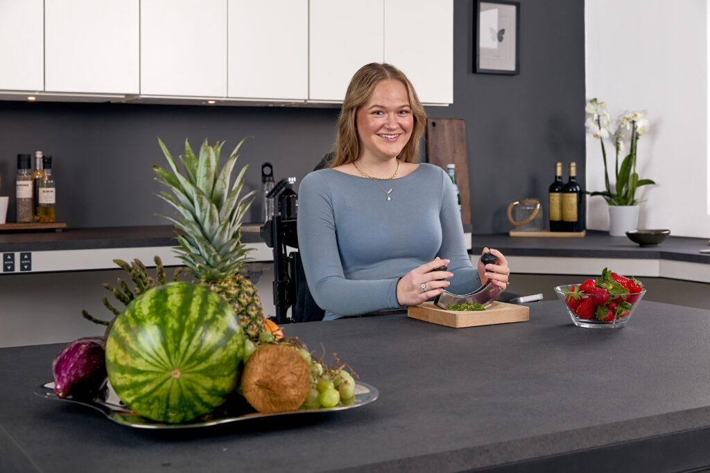 Smiling wheelchair user cooking independently at a Ropox height-adjustable worktop