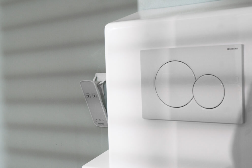 Close-up of Ropox toilet lifter wireless hand control mounted on cistern