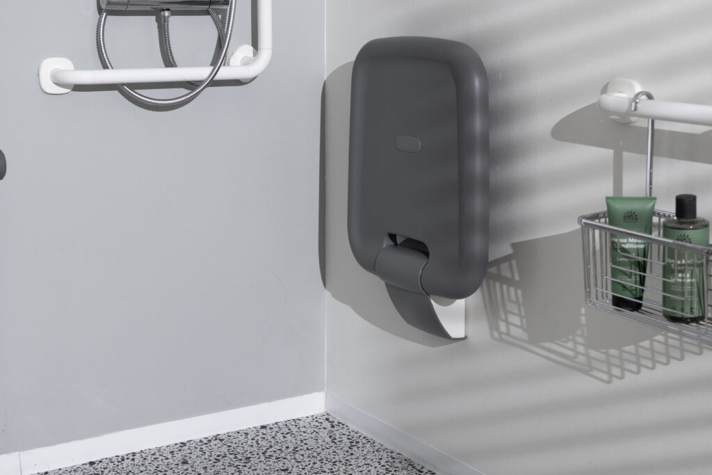 Ropox foldable shower seat in folded position mounted on accessible bathroom wall