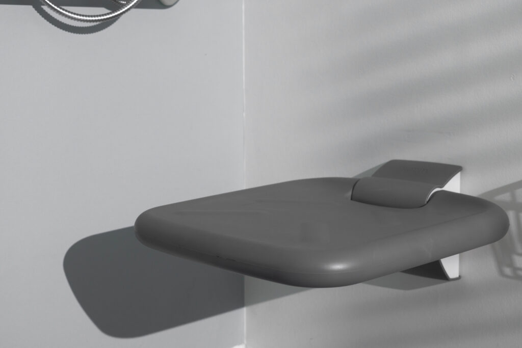 Ropox foldable shower seat with soft grey padded surface, wall-mounted