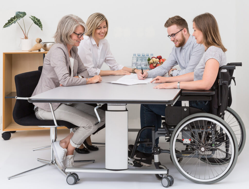 Four colleagues including a wheelchair user collaborating at a Ropox Vision Group table